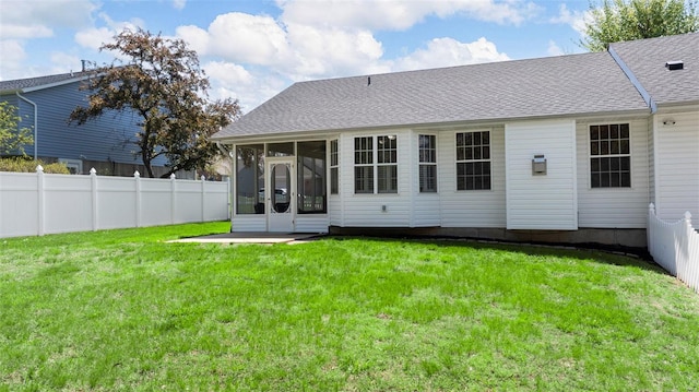 rear view of house with a lawn, a sunroom, and fence