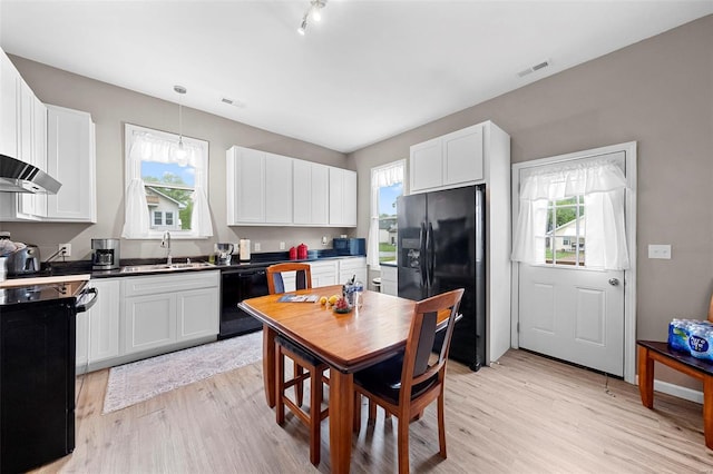 kitchen featuring a sink, light wood finished floors, white cabinetry, visible vents, and black appliances
