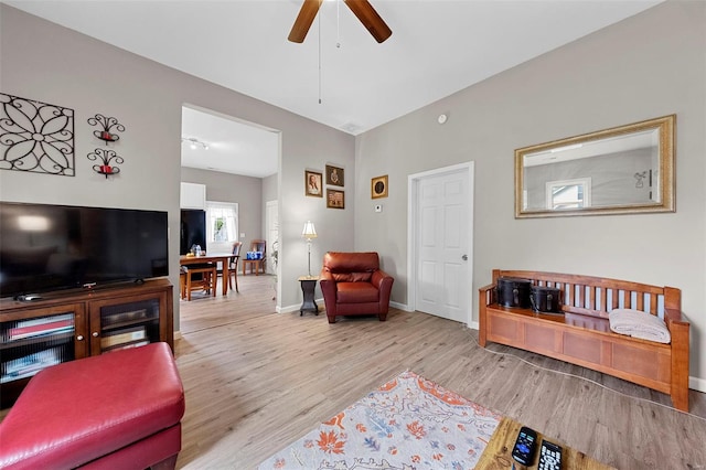 living area featuring baseboards, ceiling fan, and wood finished floors