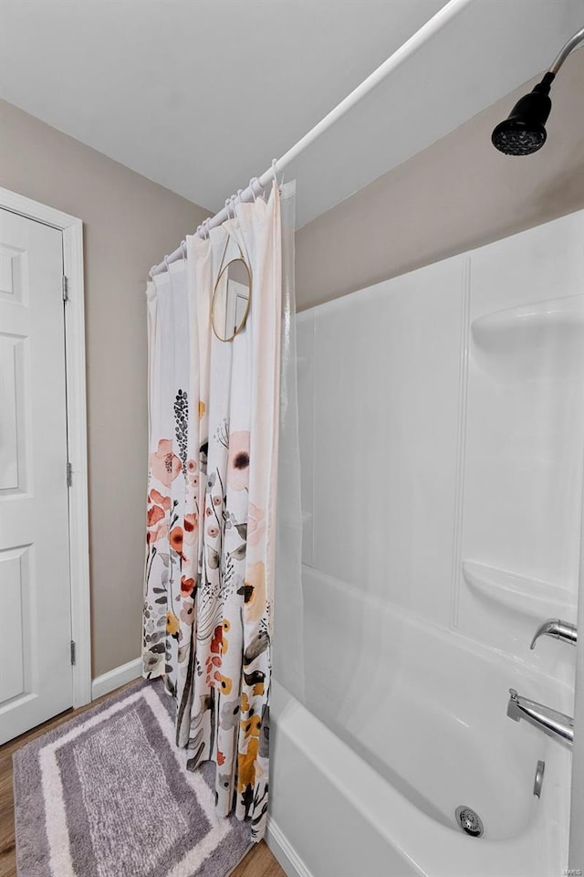 full bath featuring shower / bath combo and wood finished floors