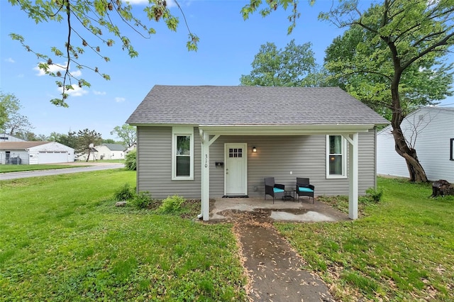 view of front of home featuring a patio, a shingled roof, and a front lawn