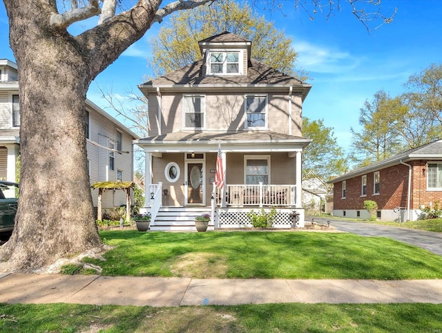 american foursquare style home featuring a porch and a front lawn