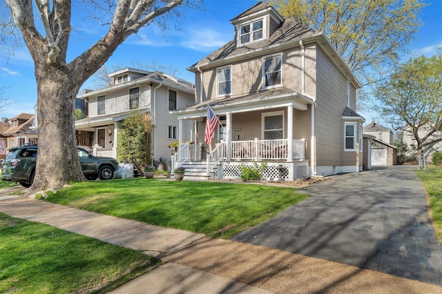 american foursquare style home with an outbuilding, covered porch, a front yard, and a garage