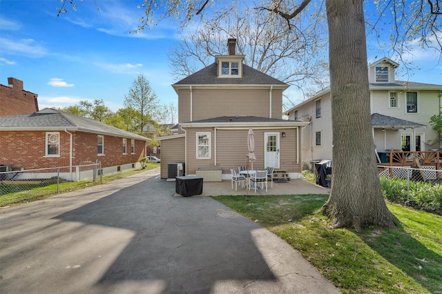 back of property with fence, a chimney, entry steps, and a patio