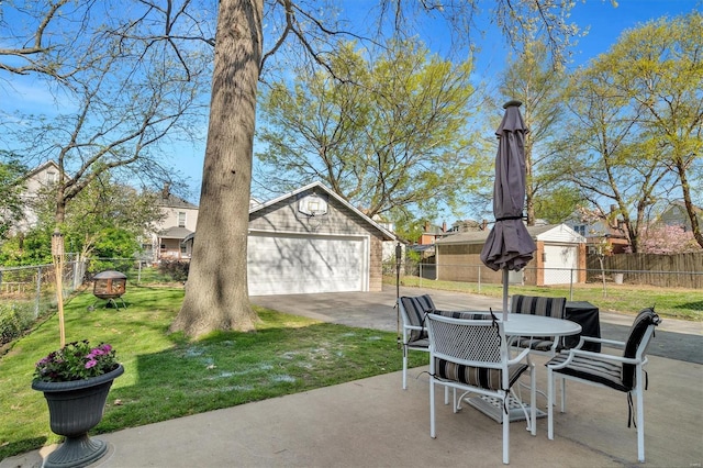 view of patio / terrace featuring an outdoor structure, a detached garage, outdoor dining area, and a fenced backyard