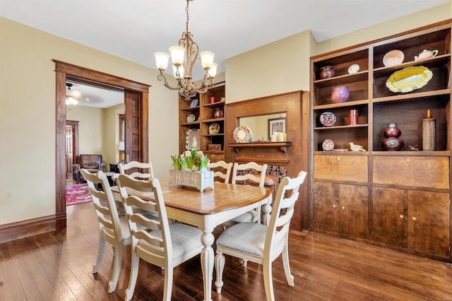 dining area with baseboards, built in features, hardwood / wood-style flooring, and an inviting chandelier