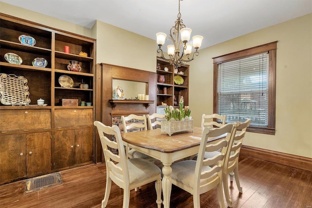 dining area with wood finished floors, visible vents, baseboards, and a notable chandelier