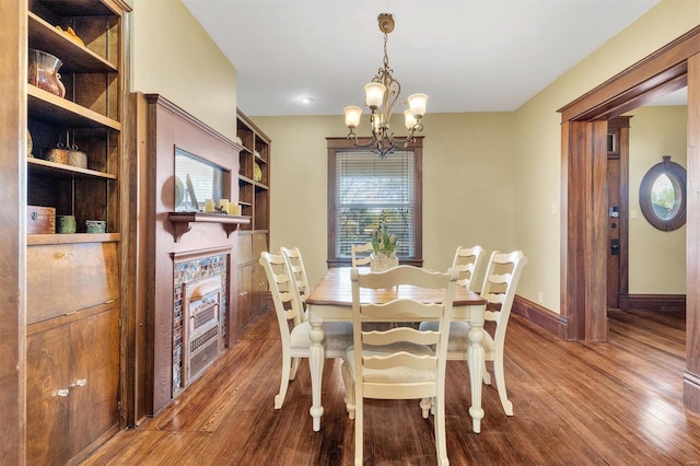 dining space featuring baseboards, a chandelier, wood finished floors, and built in features