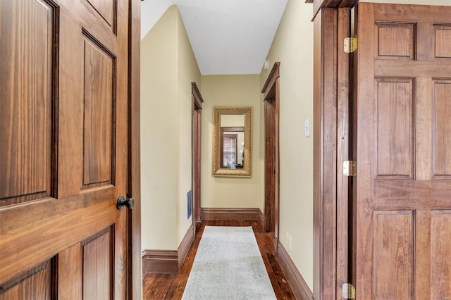 hallway featuring dark wood finished floors and baseboards