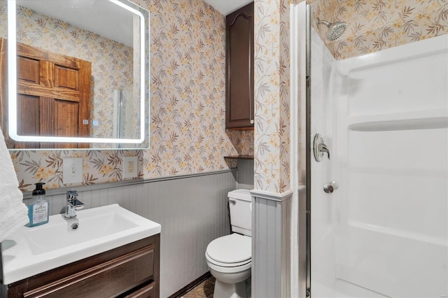 bathroom with wallpapered walls, walk in shower, toilet, and wainscoting
