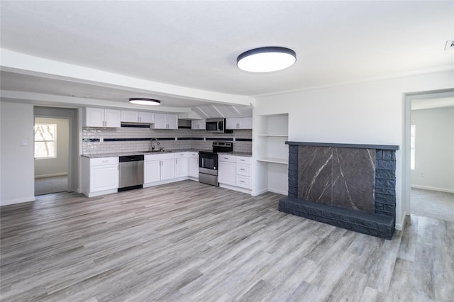 kitchen with white cabinets, light wood finished floors, stainless steel appliances, and a sink