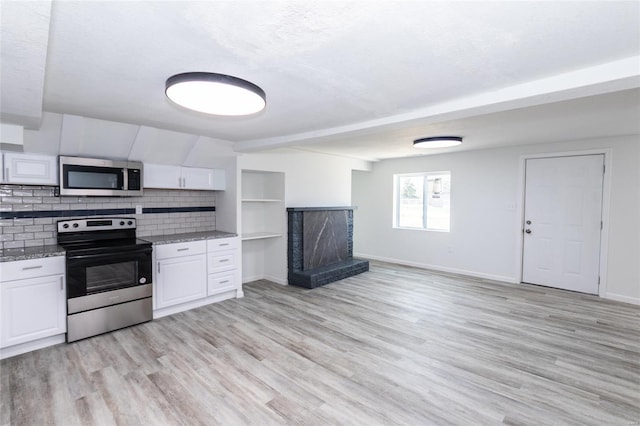 kitchen with stainless steel appliances, a fireplace, light wood-style flooring, and white cabinetry