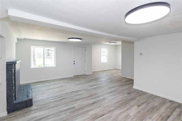 unfurnished living room with light wood-style flooring, baseboards, and a high end fireplace