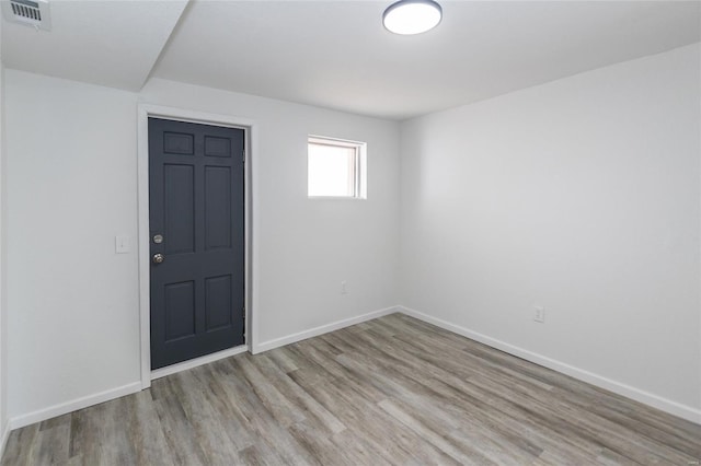 spare room featuring baseboards, wood finished floors, and visible vents
