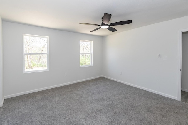 carpeted spare room featuring ceiling fan and baseboards
