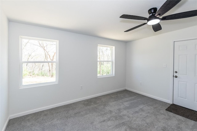 carpeted empty room featuring baseboards and a ceiling fan