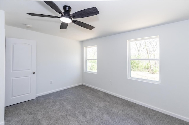 carpeted spare room featuring a ceiling fan and baseboards
