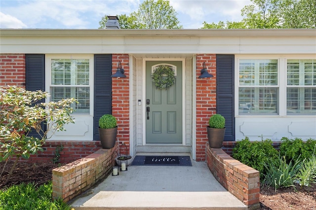 entrance to property with a chimney and brick siding