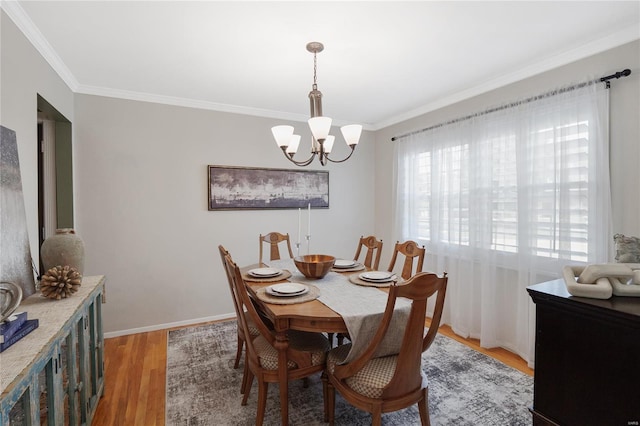 dining room with crown molding, light wood-style floors, baseboards, and a notable chandelier