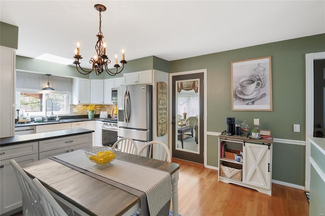 dining space with baseboards, an inviting chandelier, and light wood finished floors