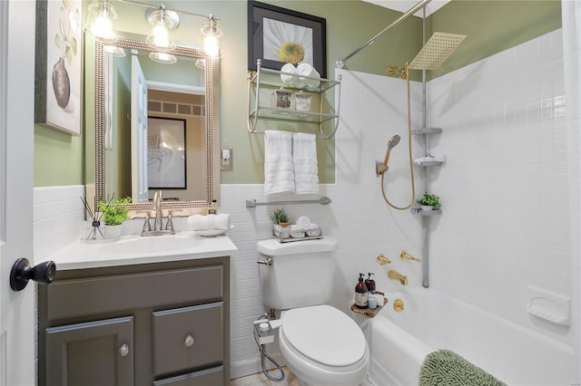 full bath with shower / bath combination, tile walls, wainscoting, vanity, and toilet