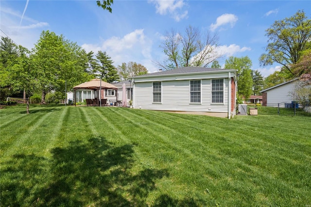 back of property featuring a lawn, fence, and a gazebo