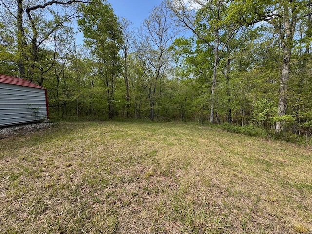 view of yard with a wooded view and an outdoor structure