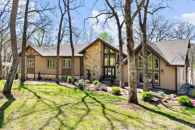 rear view of house with a lawn and stone siding