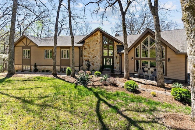 rear view of house featuring a yard and stone siding
