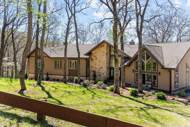 view of front facade with a front yard, a chimney, and stone siding