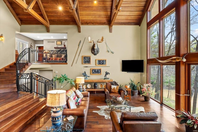 living room featuring wood-type flooring, a towering ceiling, beam ceiling, stairway, and wooden ceiling
