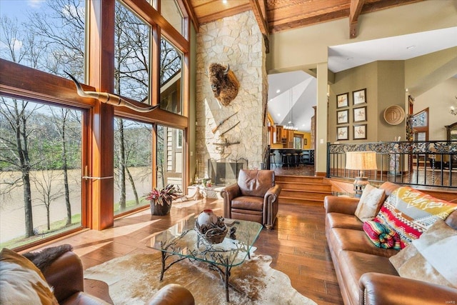 living area featuring beamed ceiling, high vaulted ceiling, wood-type flooring, and a fireplace