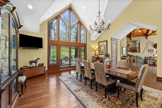 dining area featuring high vaulted ceiling, hardwood / wood-style floors, and a notable chandelier