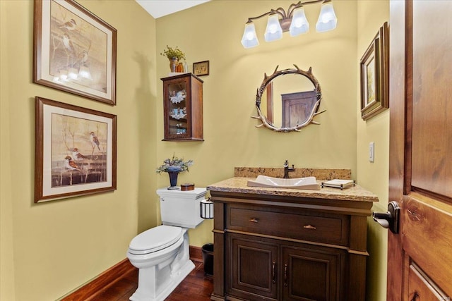 bathroom featuring vanity, baseboards, wood finished floors, and toilet