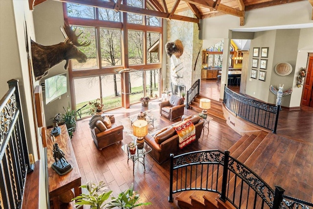 living area with beamed ceiling, wood-type flooring, high vaulted ceiling, and a wealth of natural light