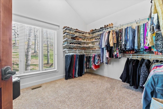 spacious closet with carpet floors, visible vents, and vaulted ceiling