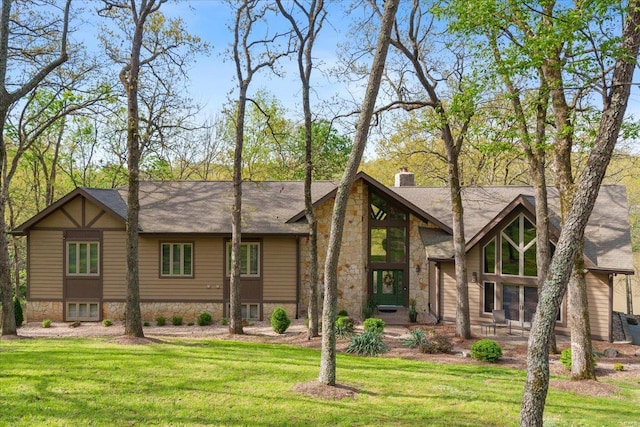view of front facade with stone siding, a front yard, and a chimney