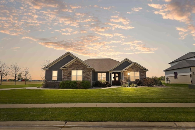 craftsman-style home with stone siding and a front lawn
