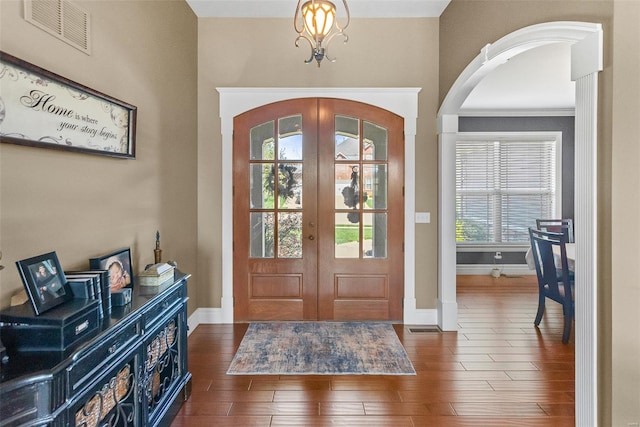 foyer entrance with french doors, arched walkways, visible vents, an inviting chandelier, and baseboards