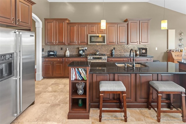 kitchen featuring a sink, decorative backsplash, a breakfast bar, pendant lighting, and stainless steel appliances