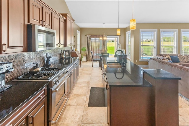 kitchen featuring a sink, decorative backsplash, open floor plan, stainless steel appliances, and a center island with sink