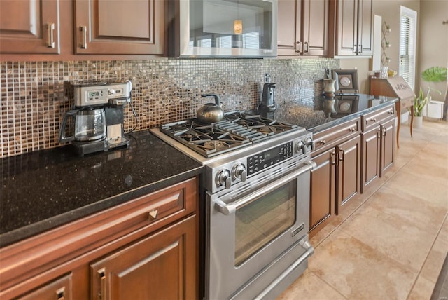 kitchen with light tile patterned floors, decorative backsplash, dark stone counters, and appliances with stainless steel finishes
