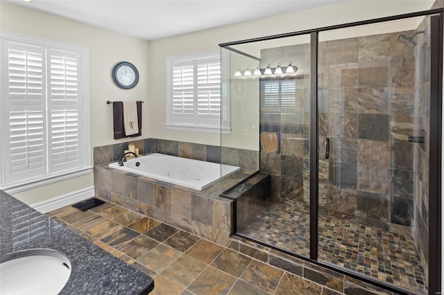 bathroom with a shower stall, a garden tub, baseboards, and a sink