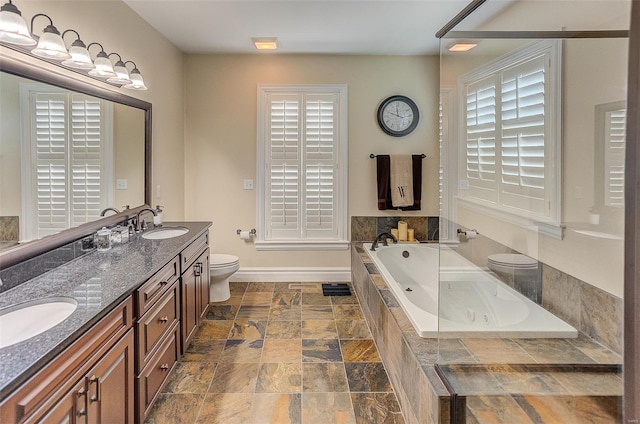 bathroom with a bath, toilet, stone finish floor, and a sink