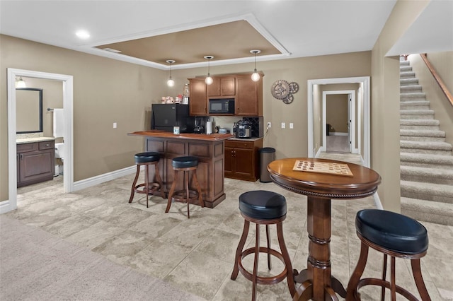 kitchen featuring decorative light fixtures, a center island, baseboards, black appliances, and a kitchen bar