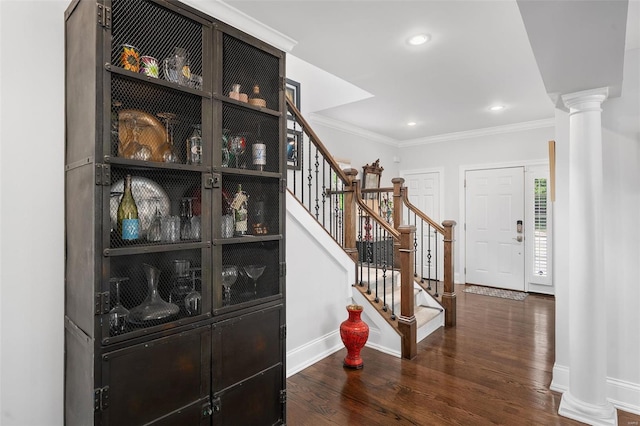 entryway with baseboards, decorative columns, wood finished floors, ornamental molding, and stairway
