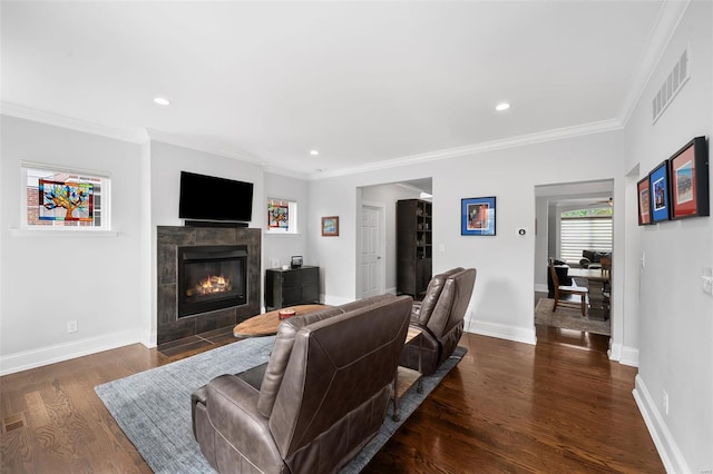 living area with visible vents, ornamental molding, a fireplace, baseboards, and dark wood-type flooring