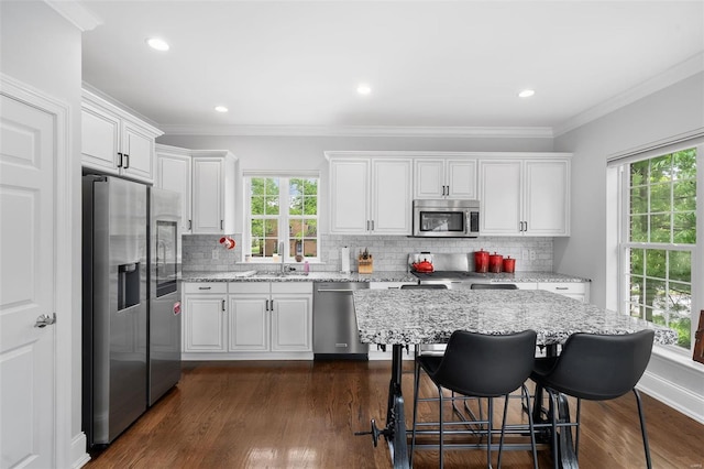 kitchen featuring a sink, appliances with stainless steel finishes, white cabinets, and backsplash