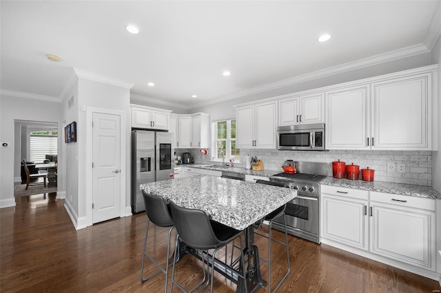 kitchen with white cabinets, stainless steel appliances, a sink, and a kitchen bar