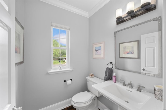 half bath featuring crown molding, toilet, baseboards, and a sink